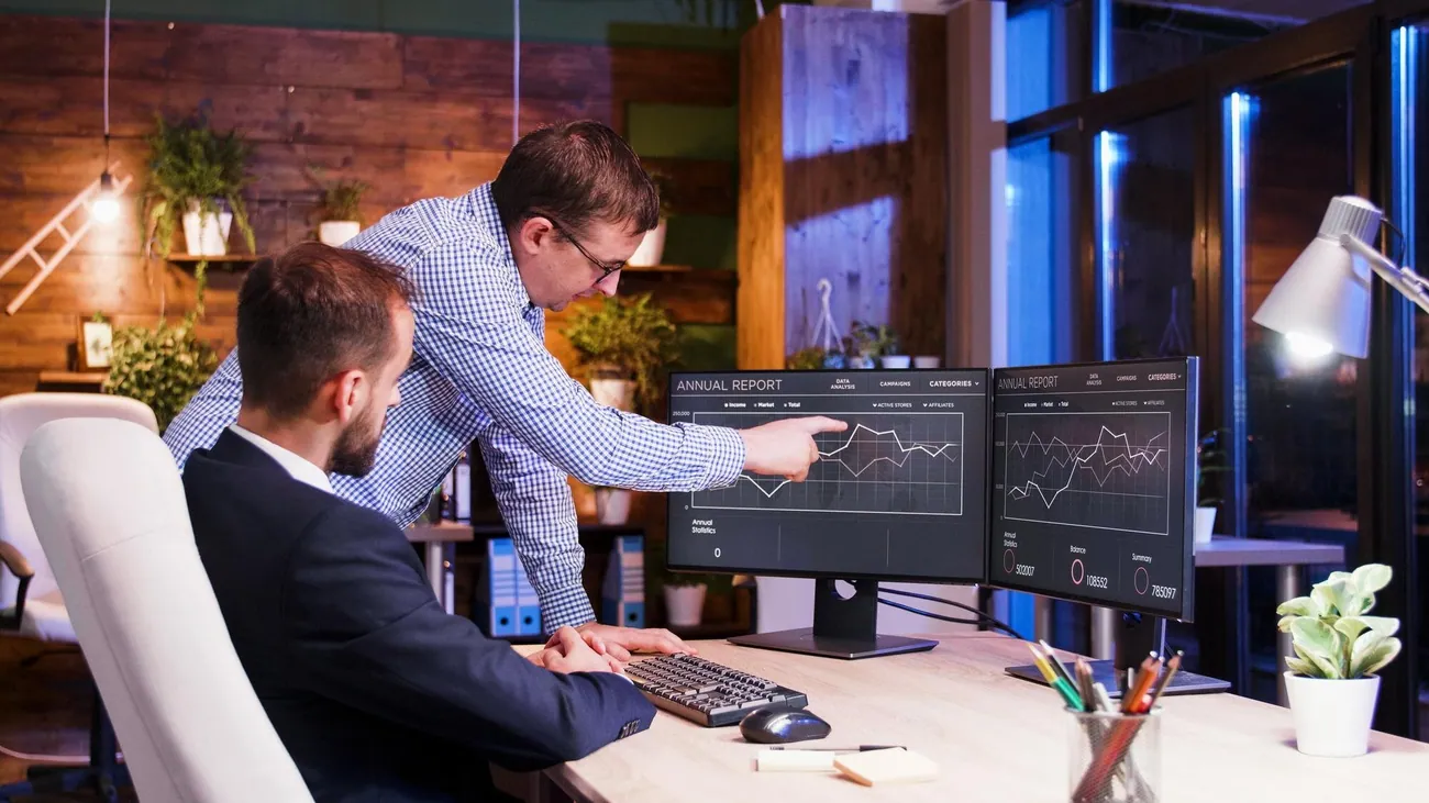 Two colleagues reviewing analytics dashboards on a monitor